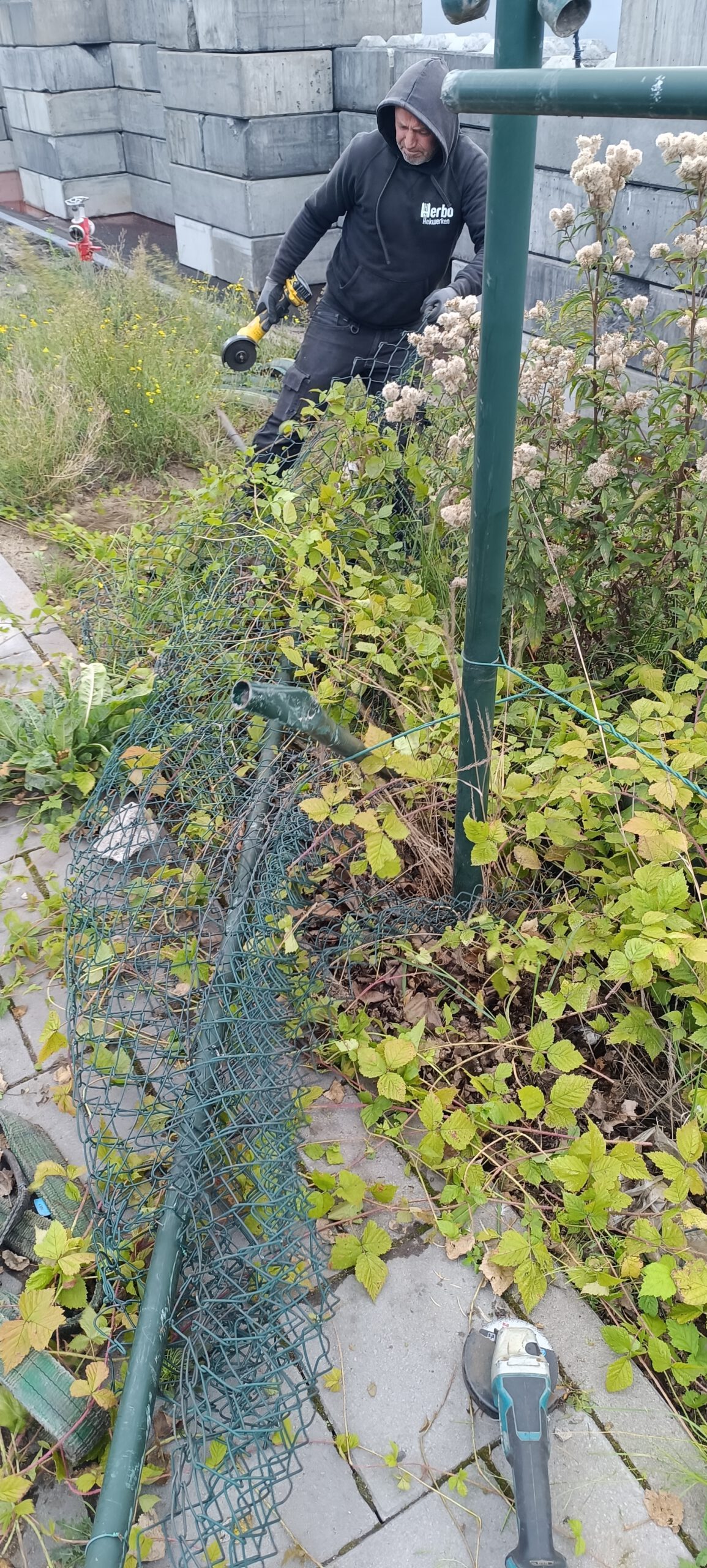 Monteur werkt aan gaashekwerk in een tuin